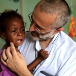 Padre Gianpietro Carraro com uma das crianças atendidas. Foto: Captura de vídeo / Missão Belém